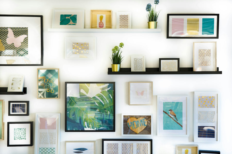 Assorted framed paintings and canvas prints on a white wall