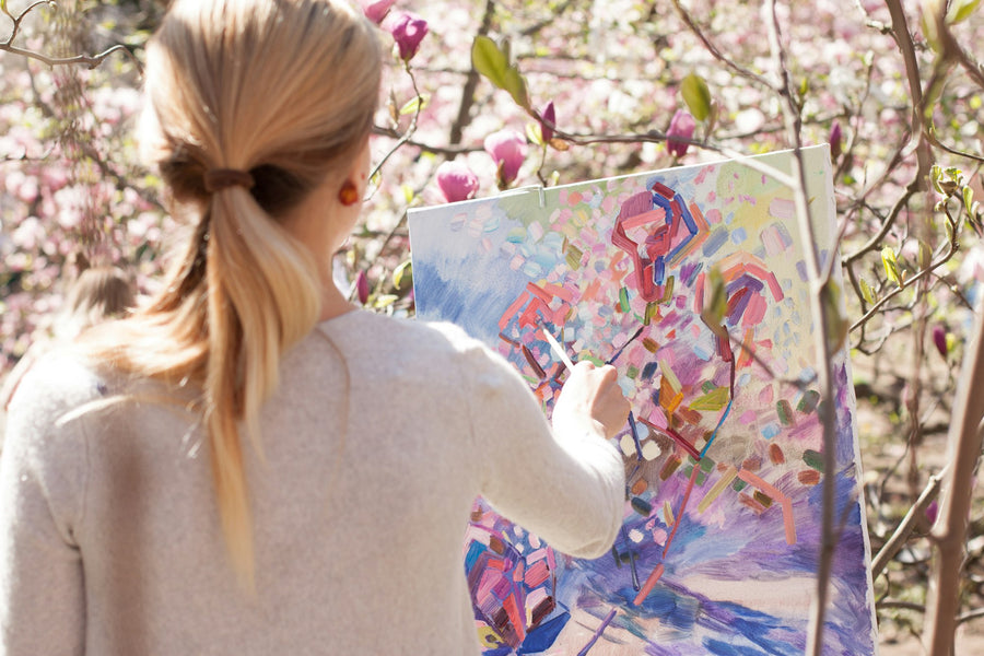 Artist holding a finished floral painting on canvas