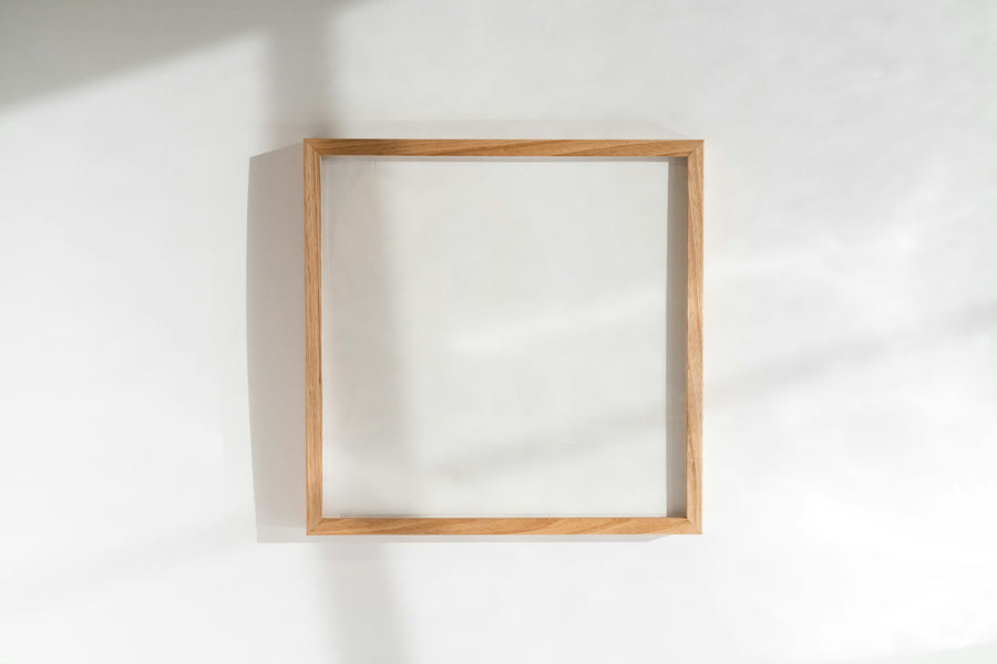 Square oak wood picture frame on a light wall